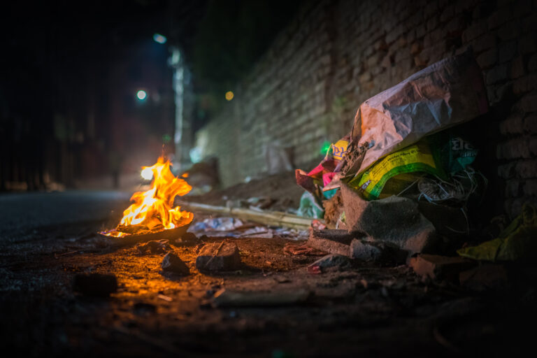 Garbage fire at night with burning rubbish on a filthy street